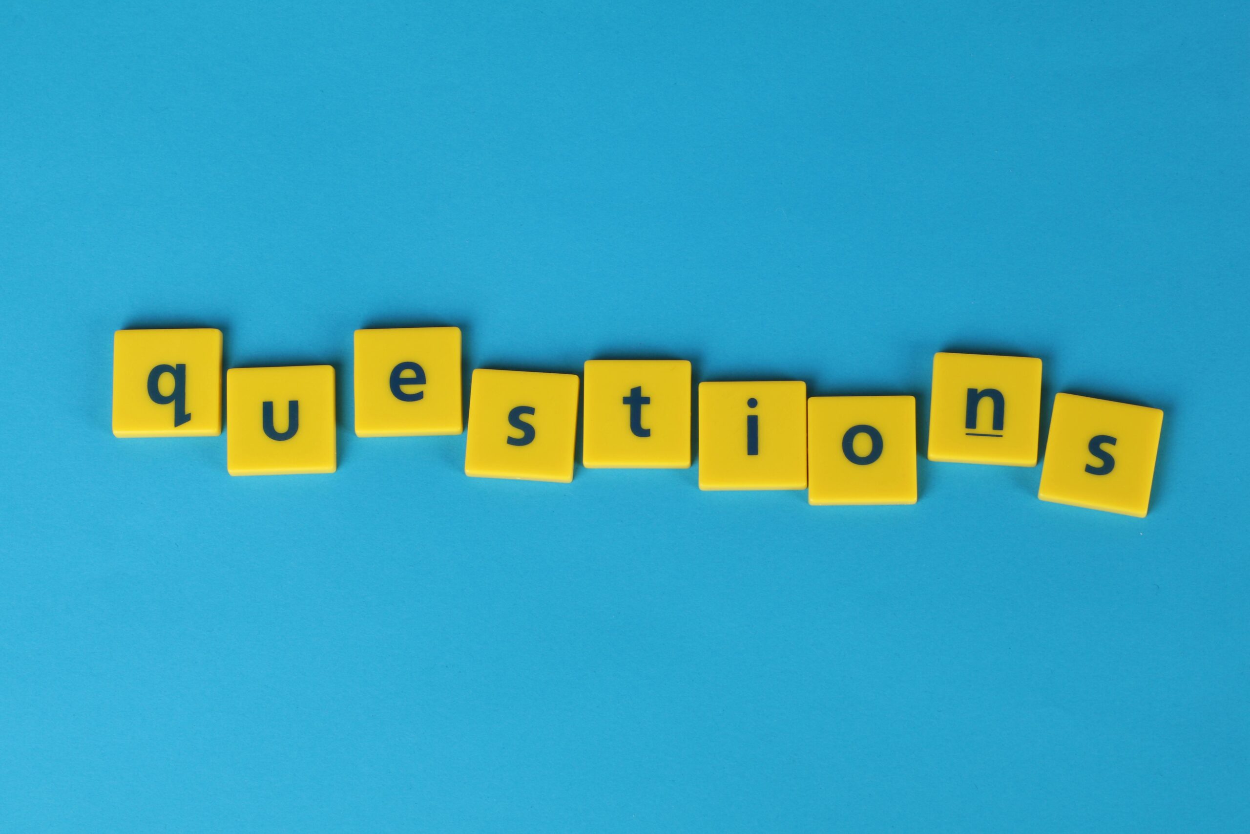 Le mot « questions » est écrit en lettres jaunes sur un fond bleu contrasté. Il s'agit de la page FAQ de l'AREAD